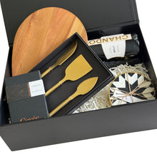 Load image into Gallery viewer, A luxury gift basket hamper featuring a wooden serving board, a bottle of Chandon Brut, a boxed set of gold-toned cheese knives, and couverture Cuvee chocolate, Clinq diamond inlay coasters

