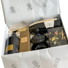Load image into Gallery viewer, An open gift box filled with premium items, including a bottle of Chandon Brut, a black and gold body wash, Glasshouse Kyoto In Bloom hand cream, a black decorative cannister, and a Côte Noire red single rose bud in a black glass jar, all arranged on white tissue paper printed with the EKA logo
