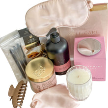 Load image into Gallery viewer, Gift hamper containing light brown hair claw, sleep mask with draw string bag, 3 black pens, Random harvest chocolate chip cookie bites, Scarlet and Grace body wash in champagne and strawberries, peppermint grove candle, bath salts and a self-care book
