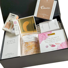 Load image into Gallery viewer, Black magnetic gift box with glow oil, vegan collagen eye masks, essential oil roller, hand and body wash, uplift bath salts, rose quartz bathing rituals, hand-poured candle and chocolatier luxurious chocolates
