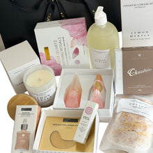 Load image into Gallery viewer, Black magnetic gift box with glow oil, vegan collagen eye masks, essential oil roller, hand and body wash, uplift bath salts, rose quartz bathing rituals, hand-poured candle and chocolatier luxurious chocolates
